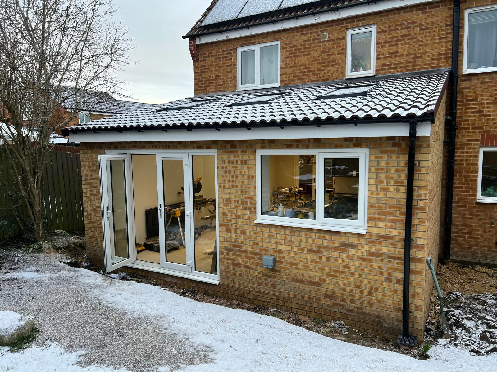 A brick house with a tiled roof and white windows.